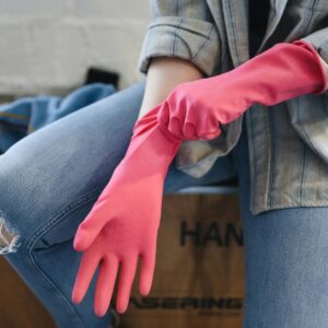 A Person Sitting on a Wooden Box Putting on Rubber Gloves